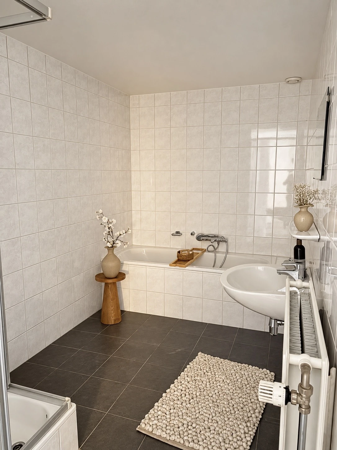 Badkamer met ligbad, wastafel en licht tegelwerk